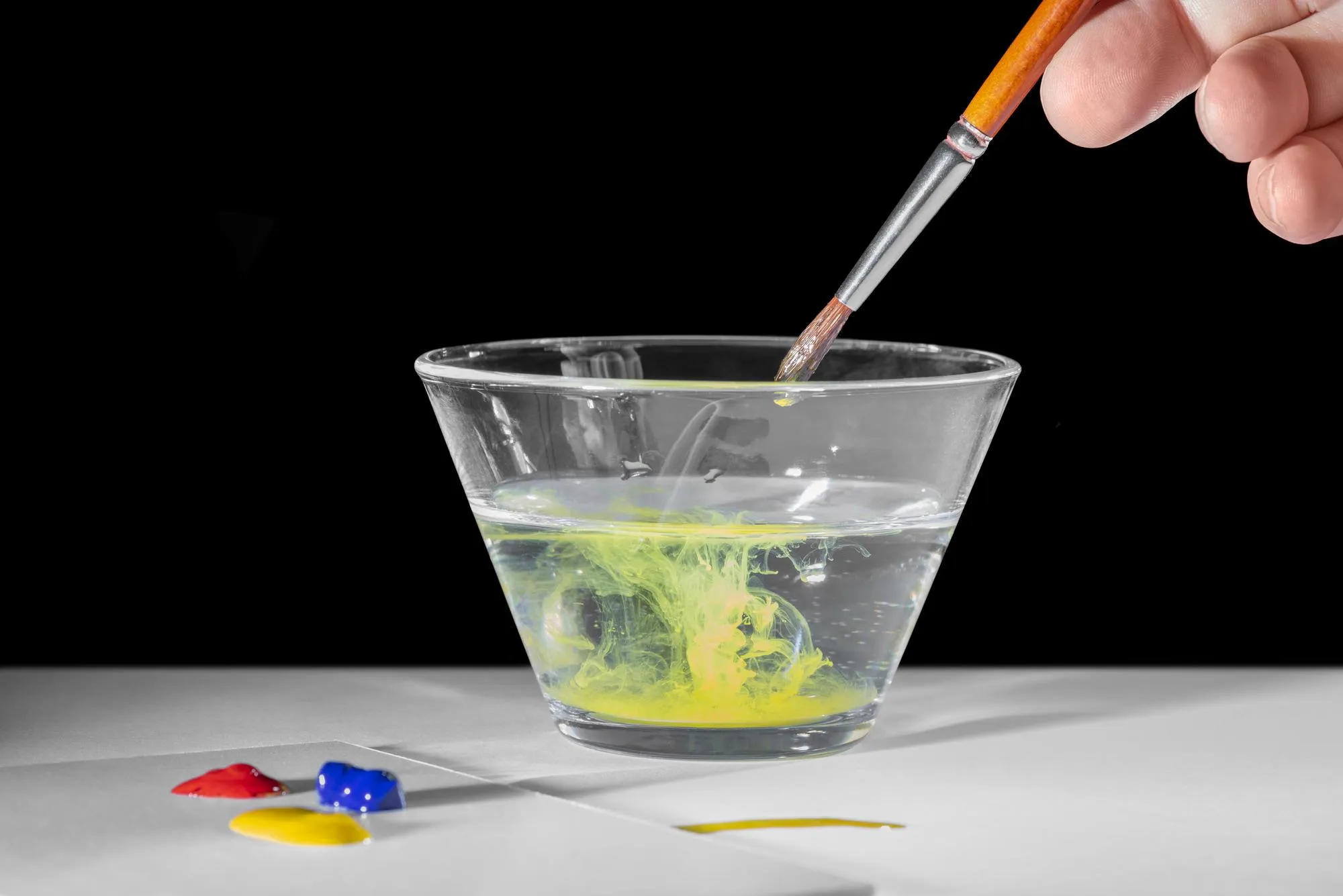 Painting scenery with hand paintbrush glass of water and some paint in dark ambiance