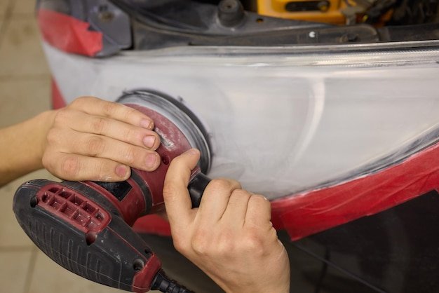 Person using a machine to polish automotive lighting on a car headlight