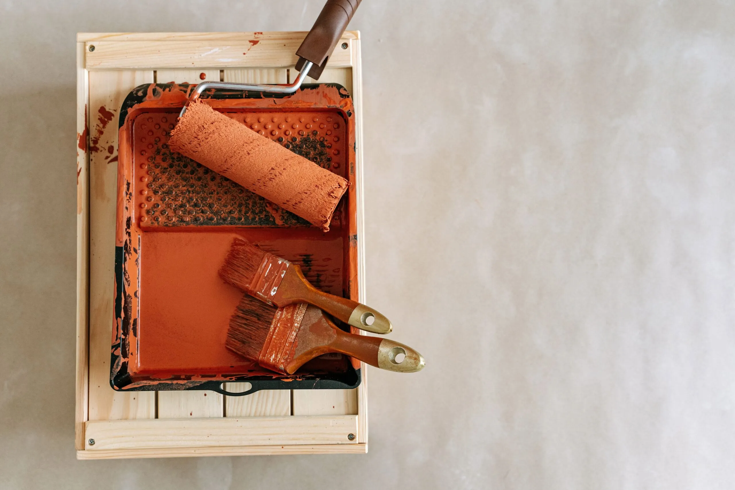 An overhead shot of paintbrushes and a roller in a tray, perfect for home renovation projects.