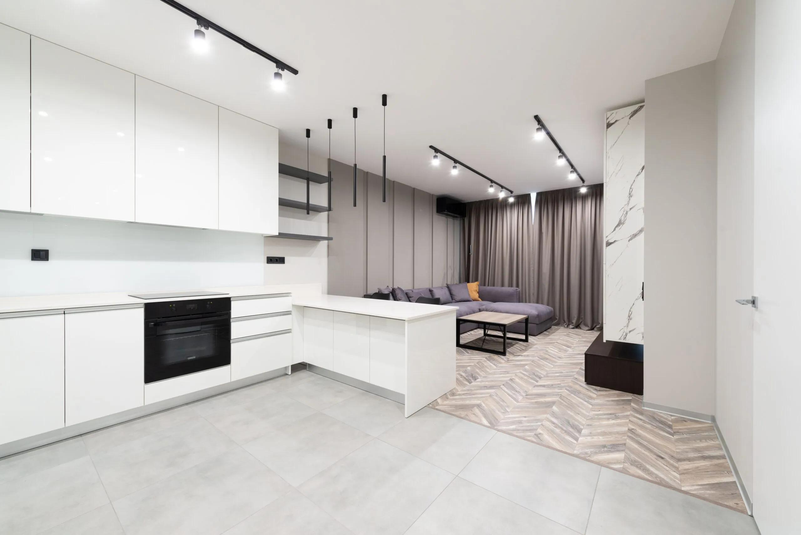 Sleek open-plan kitchen and living area with contemporary design featuring white cabinets and neutral tones.