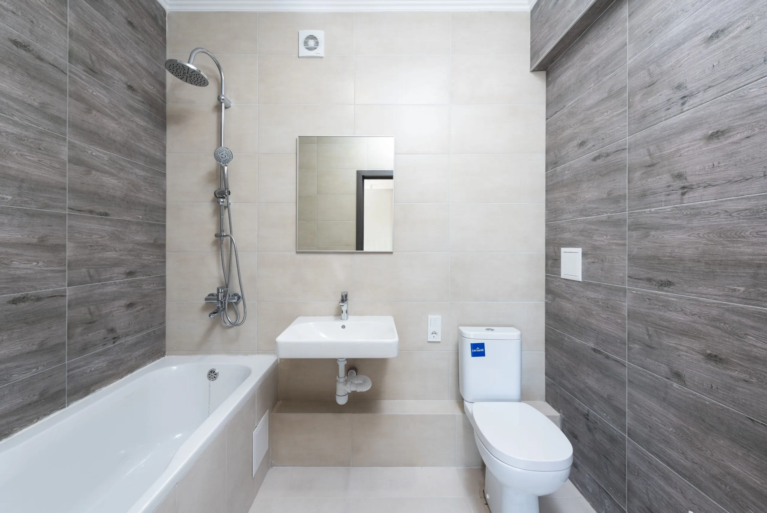 A contemporary bathroom features a bathtub, sink, and toilet with wood accents.