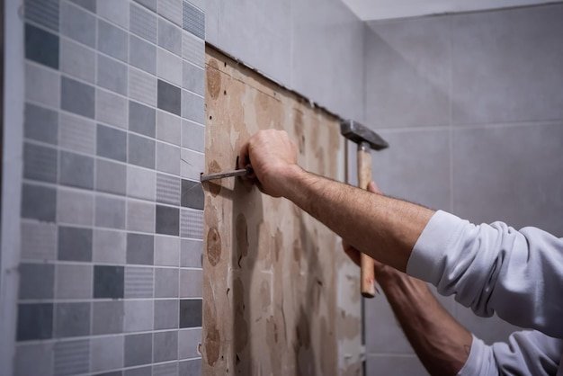 professional worker remove demolish old tiles in a bathroom with hammer and chisel