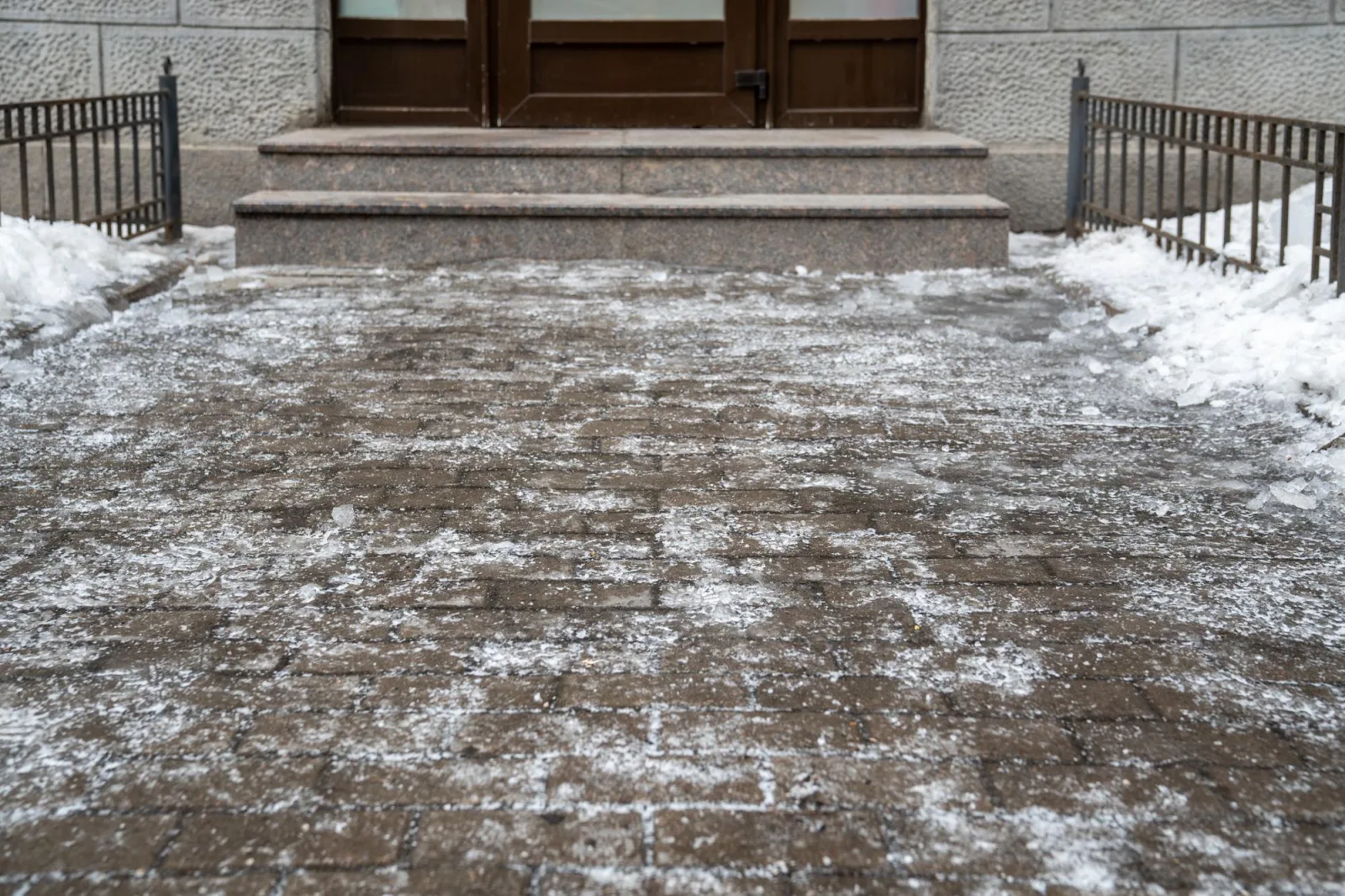 Slippery sidewalk covered with thick crust of ice in front of entrance to the building winter time