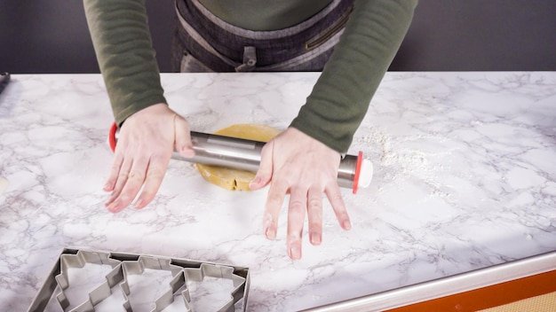 Step by step. Rolling out sugar cookie dough to bake Christmas cookies.