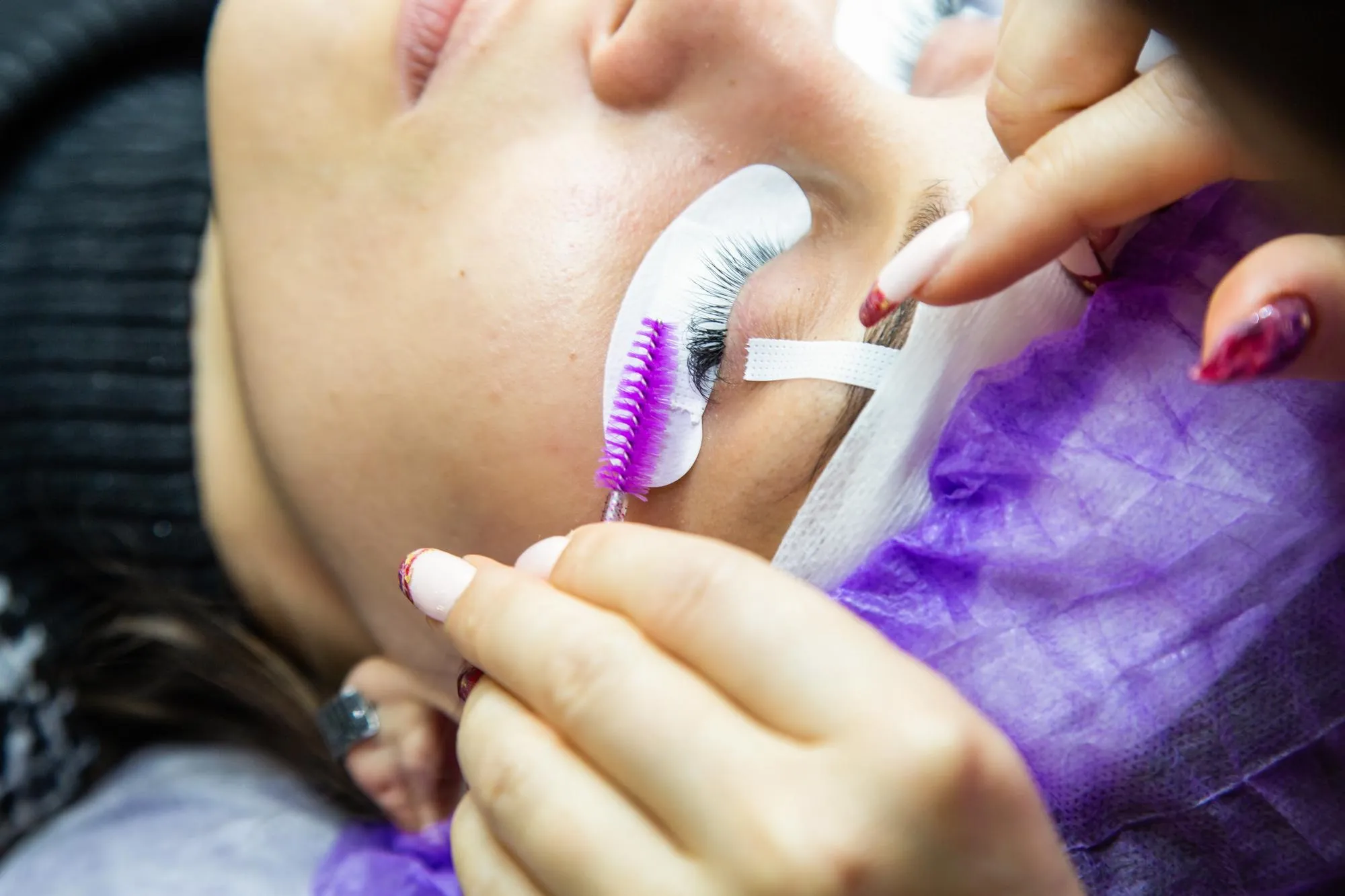 woman at spa salon applying false eyelashes
