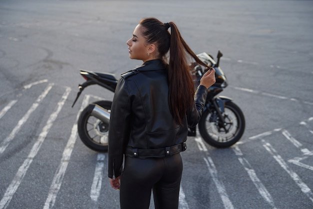 woman with long hair in a leather jacket in an underground parking lot on a motorcycle