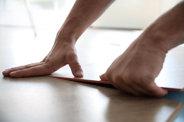 Worker installing laminated wooden floor indoors closeup
