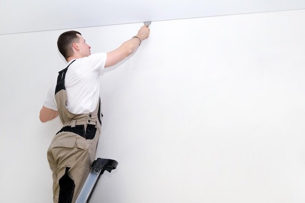 Worker installs a stretch ceiling. Construction and renovation concept