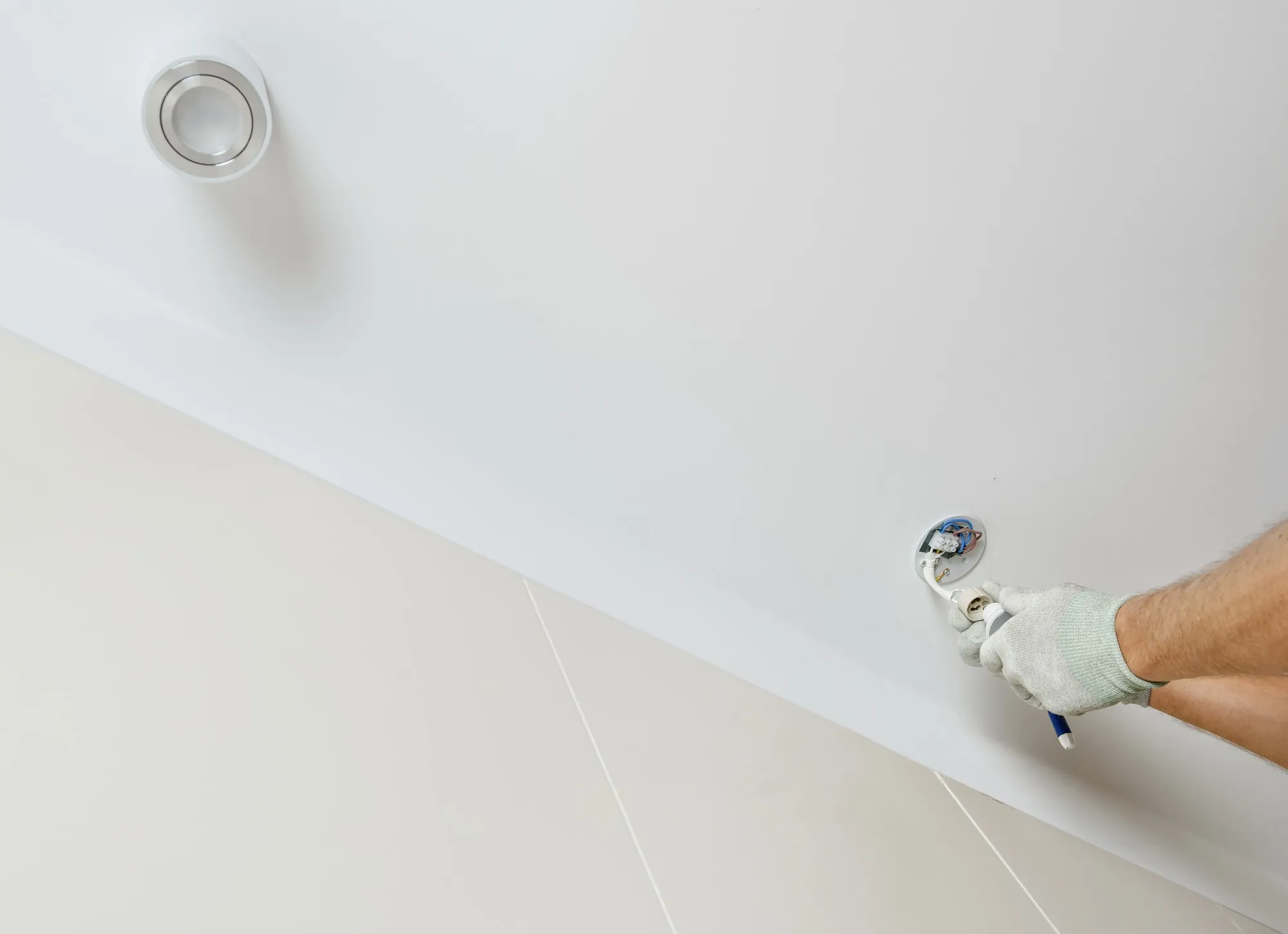 A worker is installing an LED spotlight on the suspended ceiling.