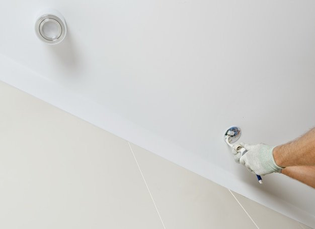 A worker is installing an LED spotlight on the suspended ceiling.