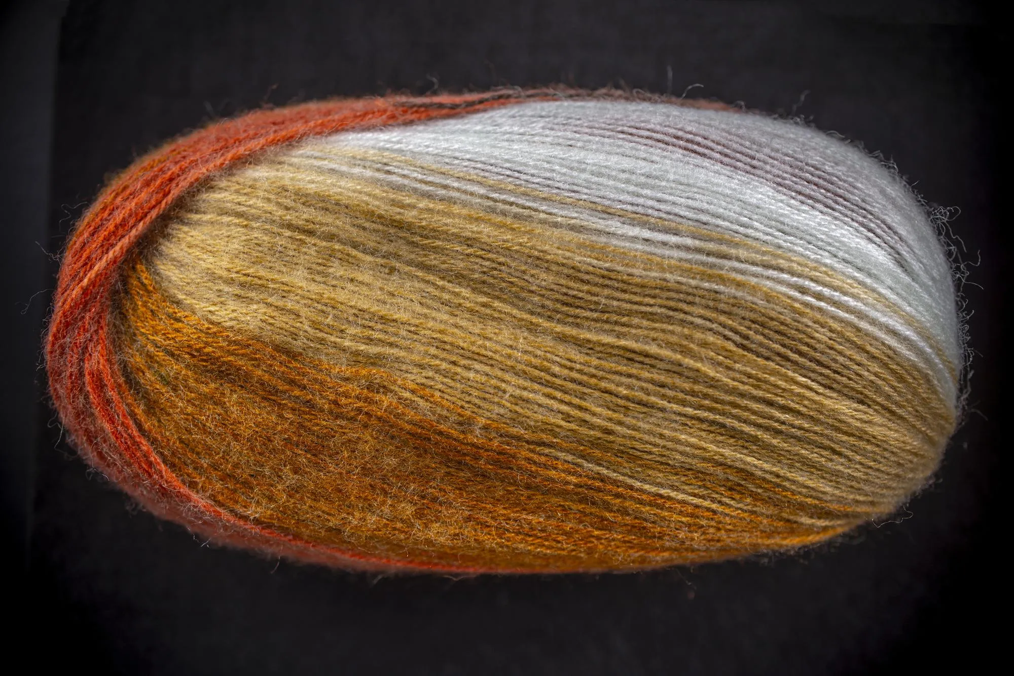 A ball of yarn with a gold and white stripe