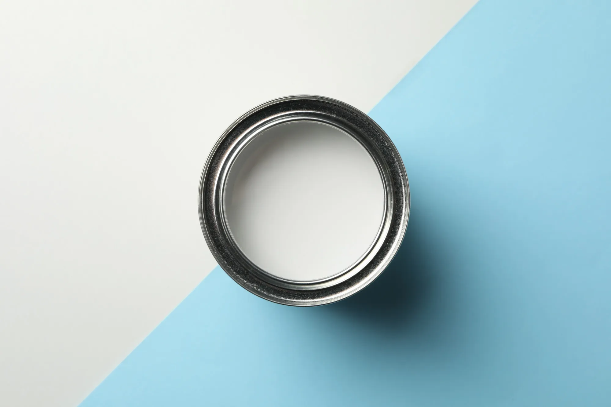 Can of white paint on two tone background, top view