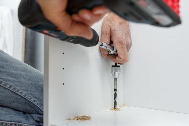 Carpenter using angle drilling bit adapter in furniture making process