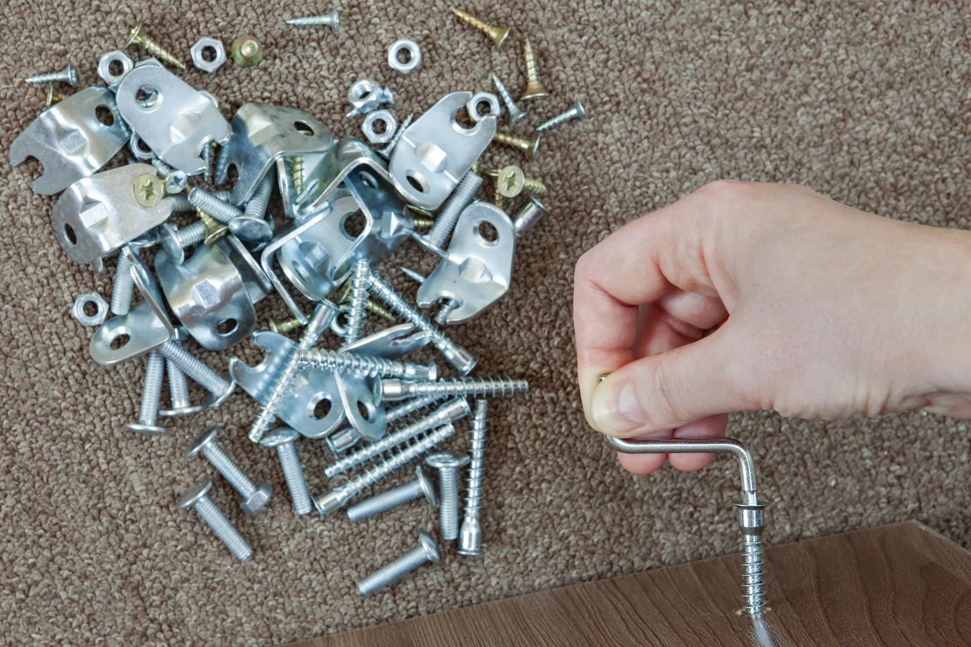 Cropped hand using hex wrench with screw at home