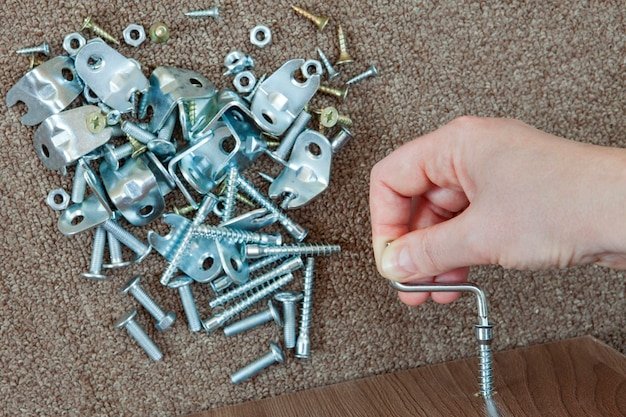 Cropped hand using hex wrench with screw at home