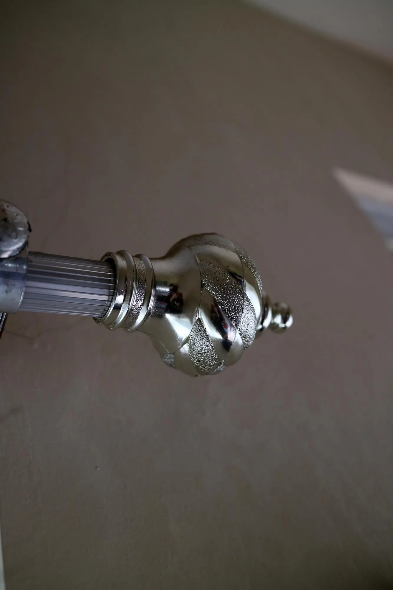 The curtain pole end cap with a round tapered shape with a chrome color made of plastic