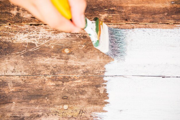diy woman hand using paintbrush decorating or painting old wood brown color to white color