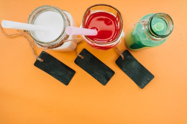 Drinks in glass bottles with straws next to dark labels 