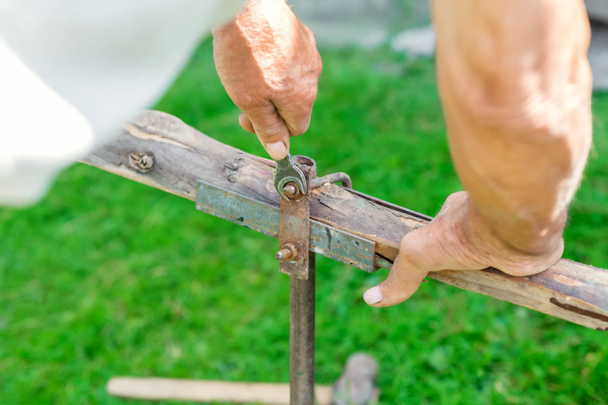 Elderly man twists the nut by wrench