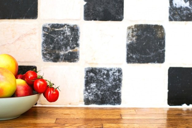 Fruit and vegetables on the kitchen top near tiled wall, tomatoes and apples, cozy design