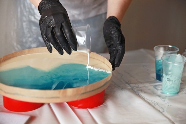 A girl in black gloves applies epoxy resin to a flat surface Master class hobby