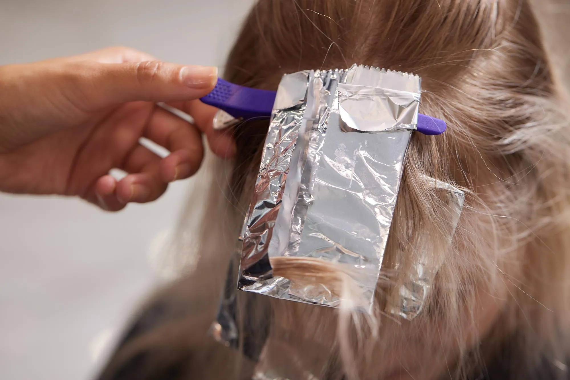 Hair stylist makes bouffant using comb on thin strands Shatush technique for hair lightening