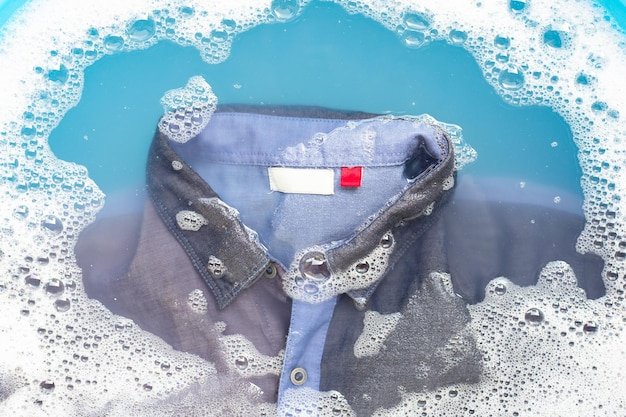 High angle view of t-shirt with soap sud in container