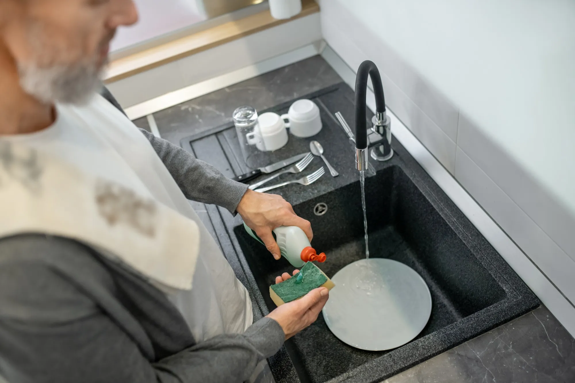 Housework. Close up of a man washing the plates in the kitchen