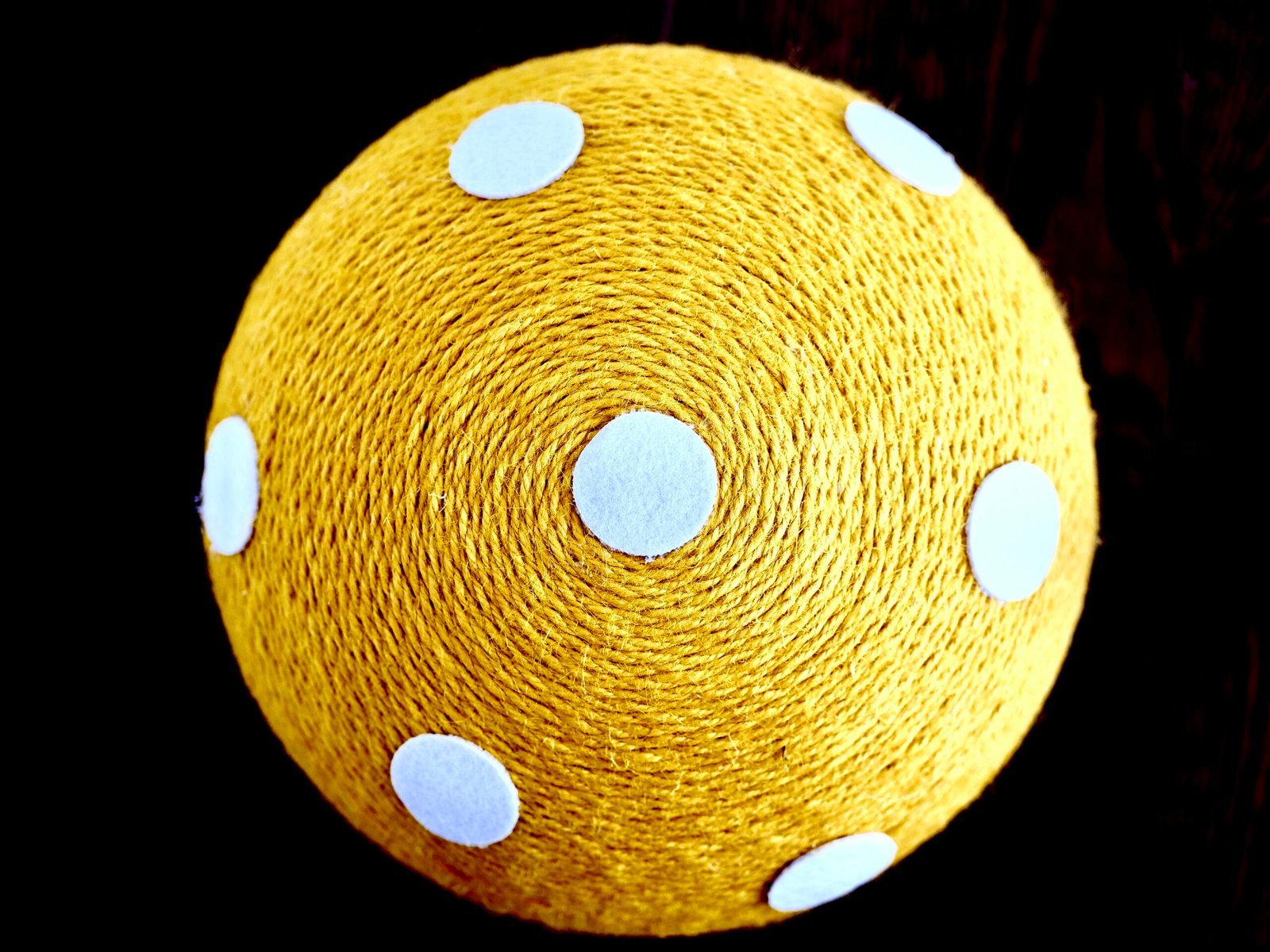 Yellow ball with white polka dots on black background