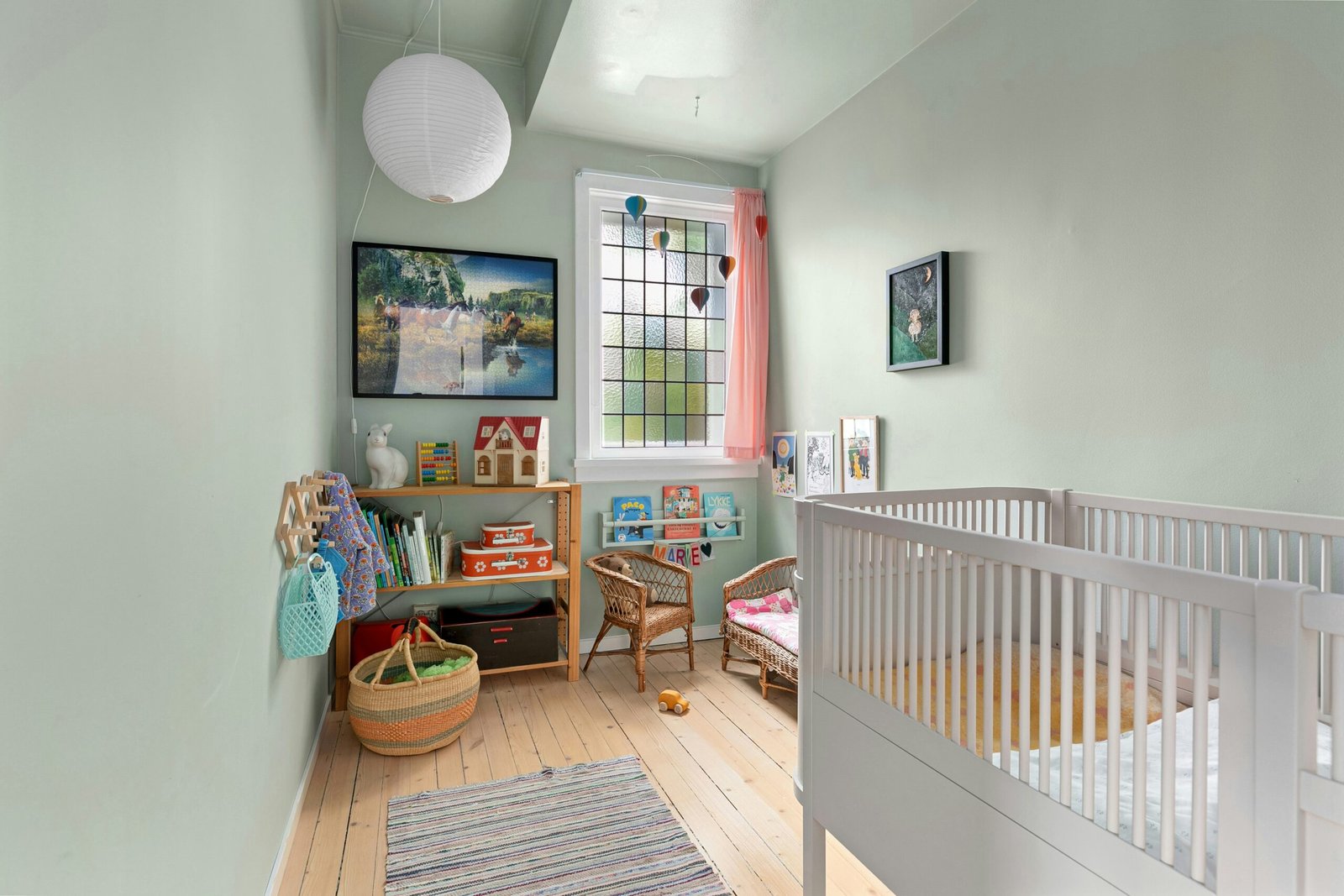 A baby's room with a white crib and wooden floors