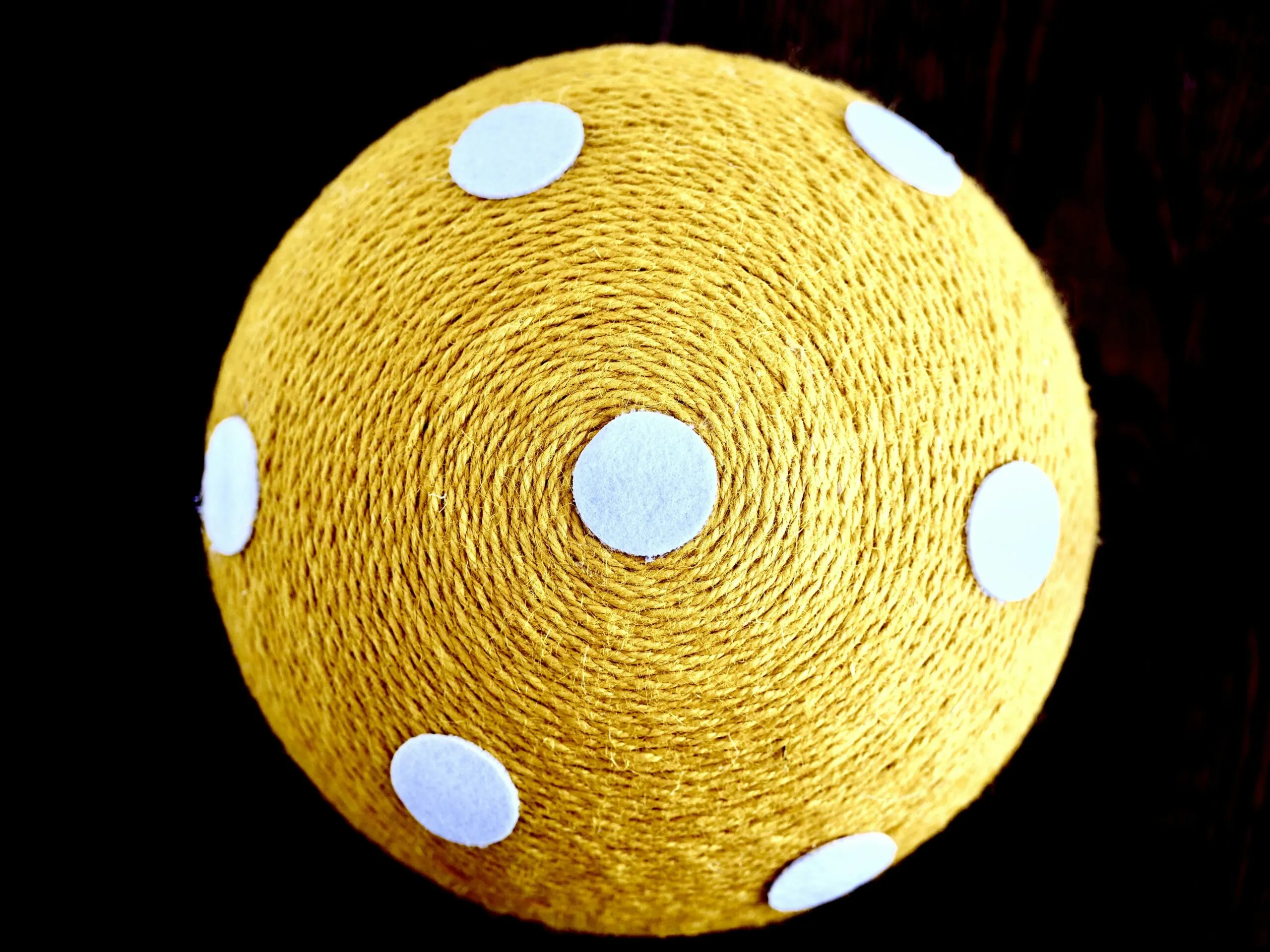 Yellow ball with white polka dots on black background