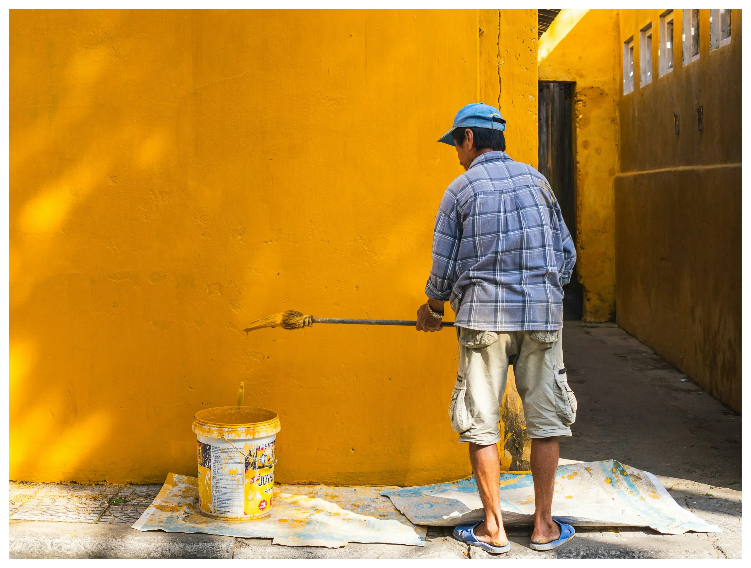 A man painting a yellow wall with a paint roller