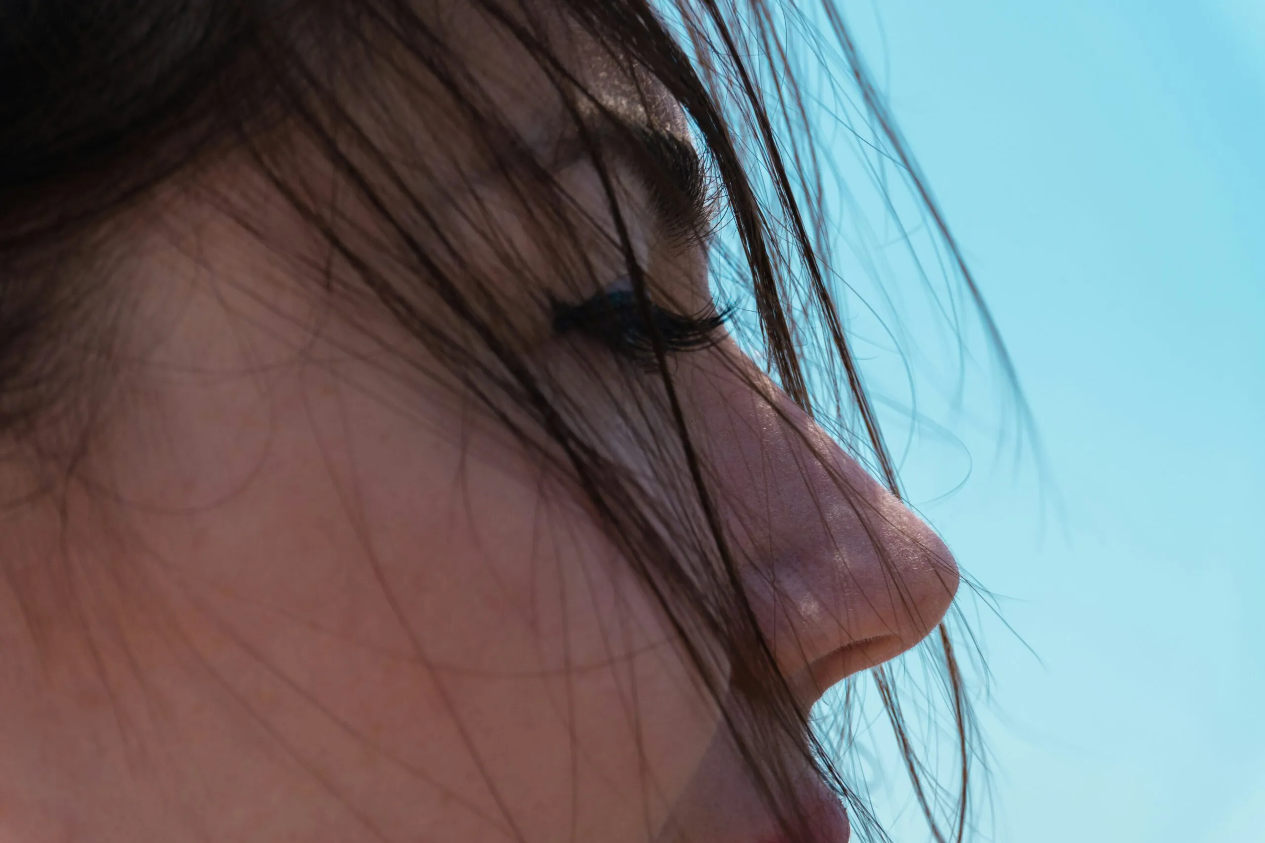 Close-up profile of a young woman against blue sky