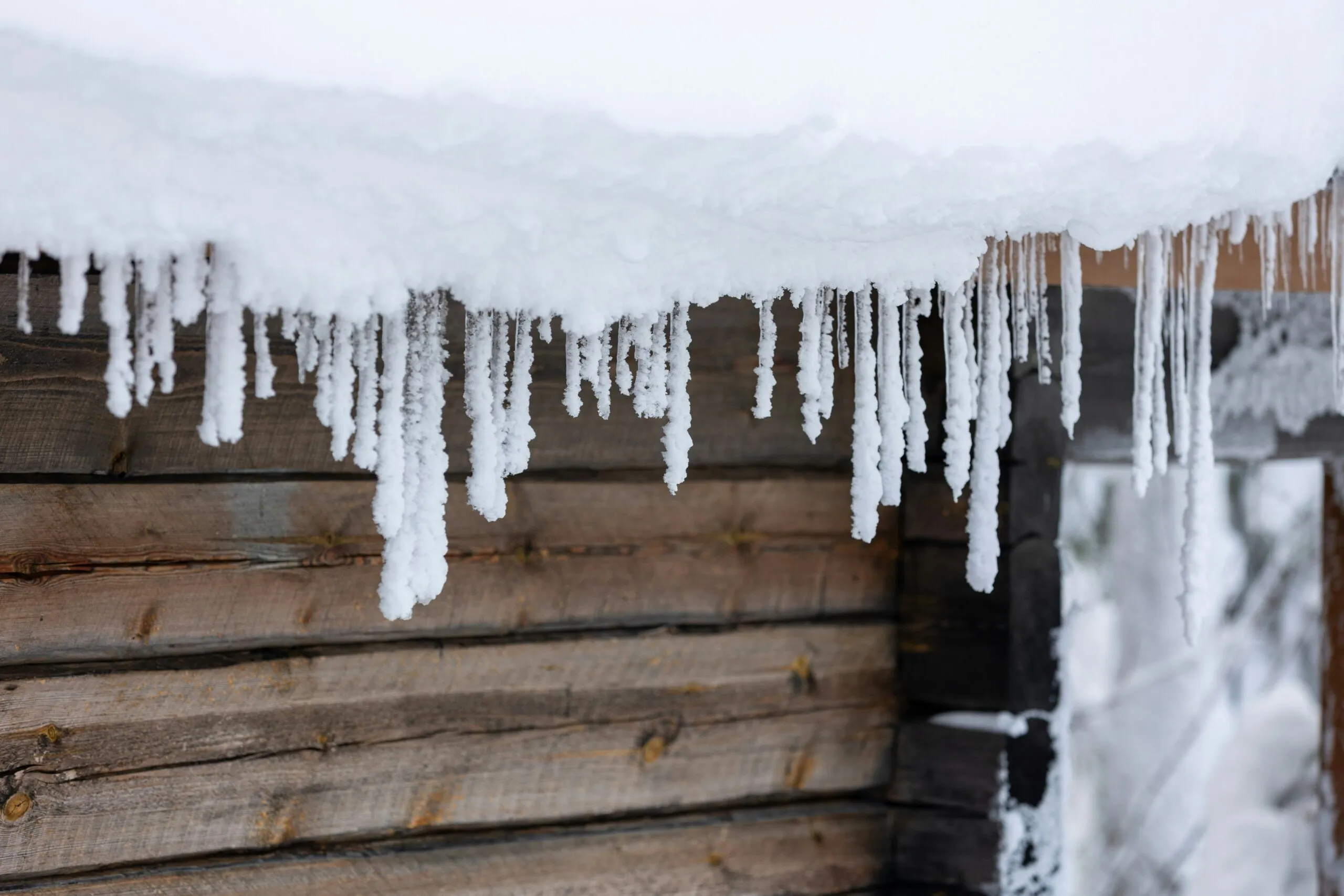 icicles are hanging from the roof of a cabin