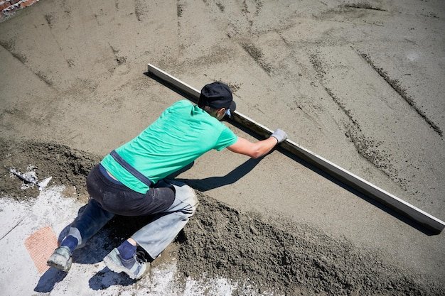 Male builder screeding floor at construction site