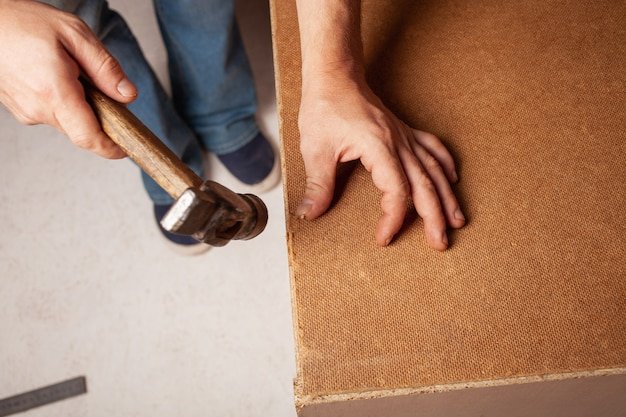 A man hammers nails into a cupboard.