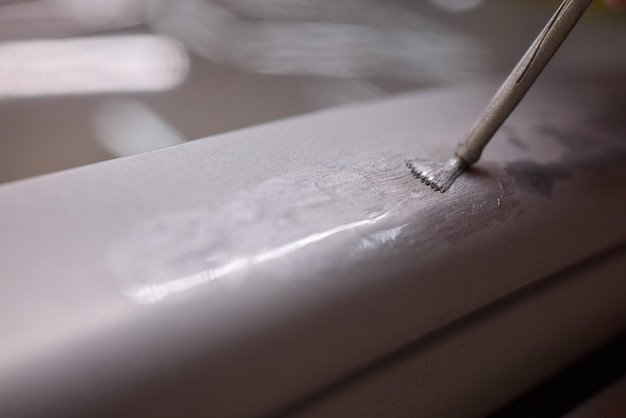 A man repaints a scratch on a car part in an auto repair shop with precision and craftsmanship