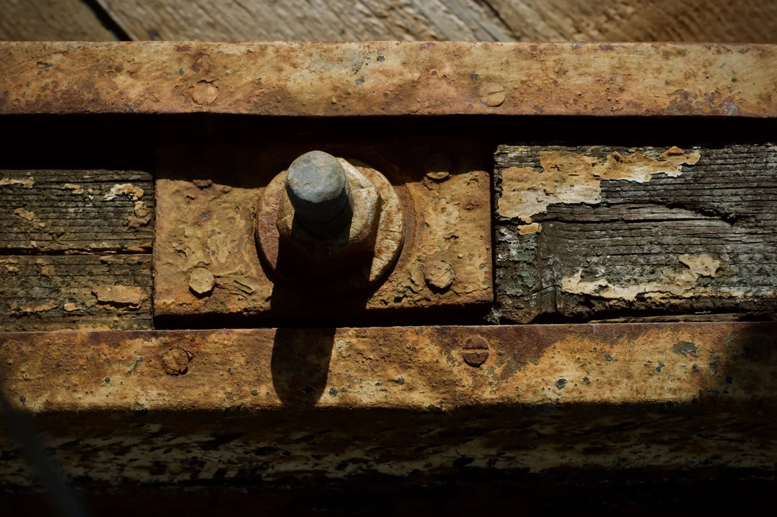 Detailed macro shot of a rusty bolt on aged wood, showcasing decay.