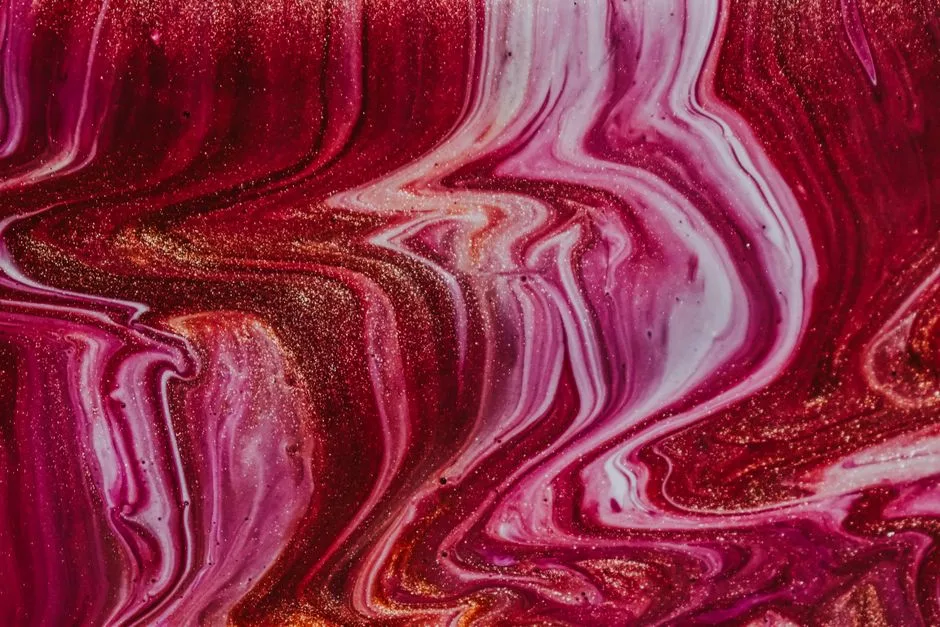 Top view closeup of shiny fuchsia colored nail polish with golden sequins smeared on surface as abstract background