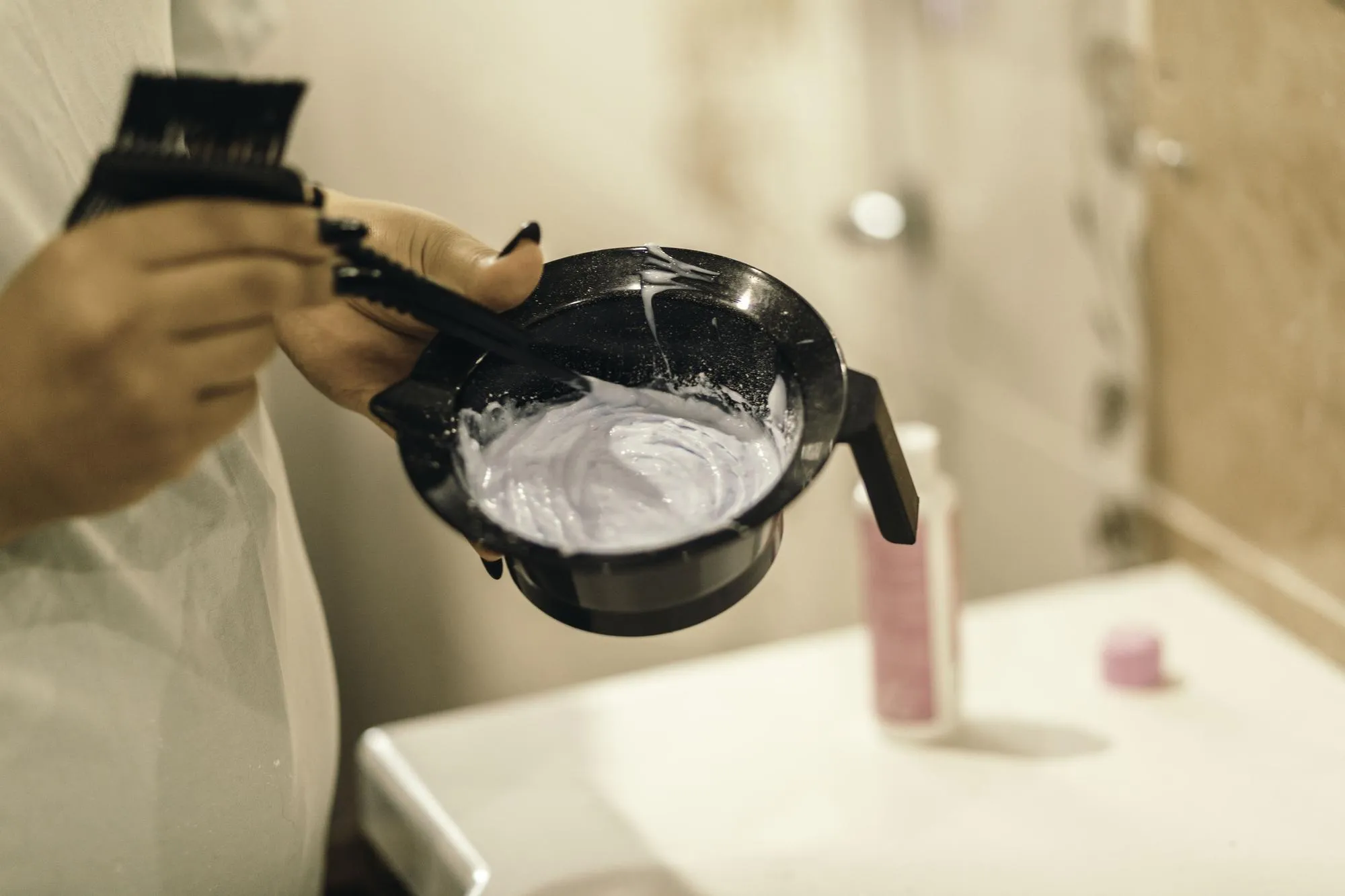 Process of preparing for hair coloring at home female hands with oxidizing in plastic bowl