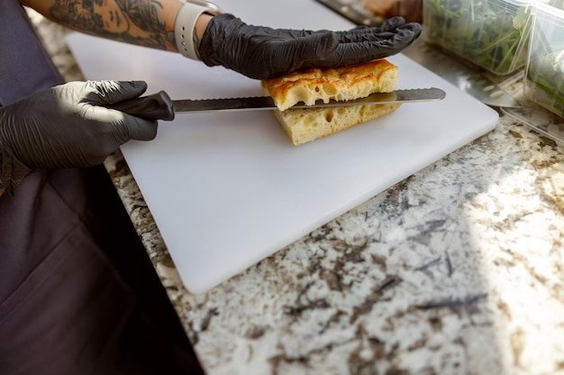 Professional Chef Skillfully Slicing a Freshly Baked Sandwich on a Marble Countertop