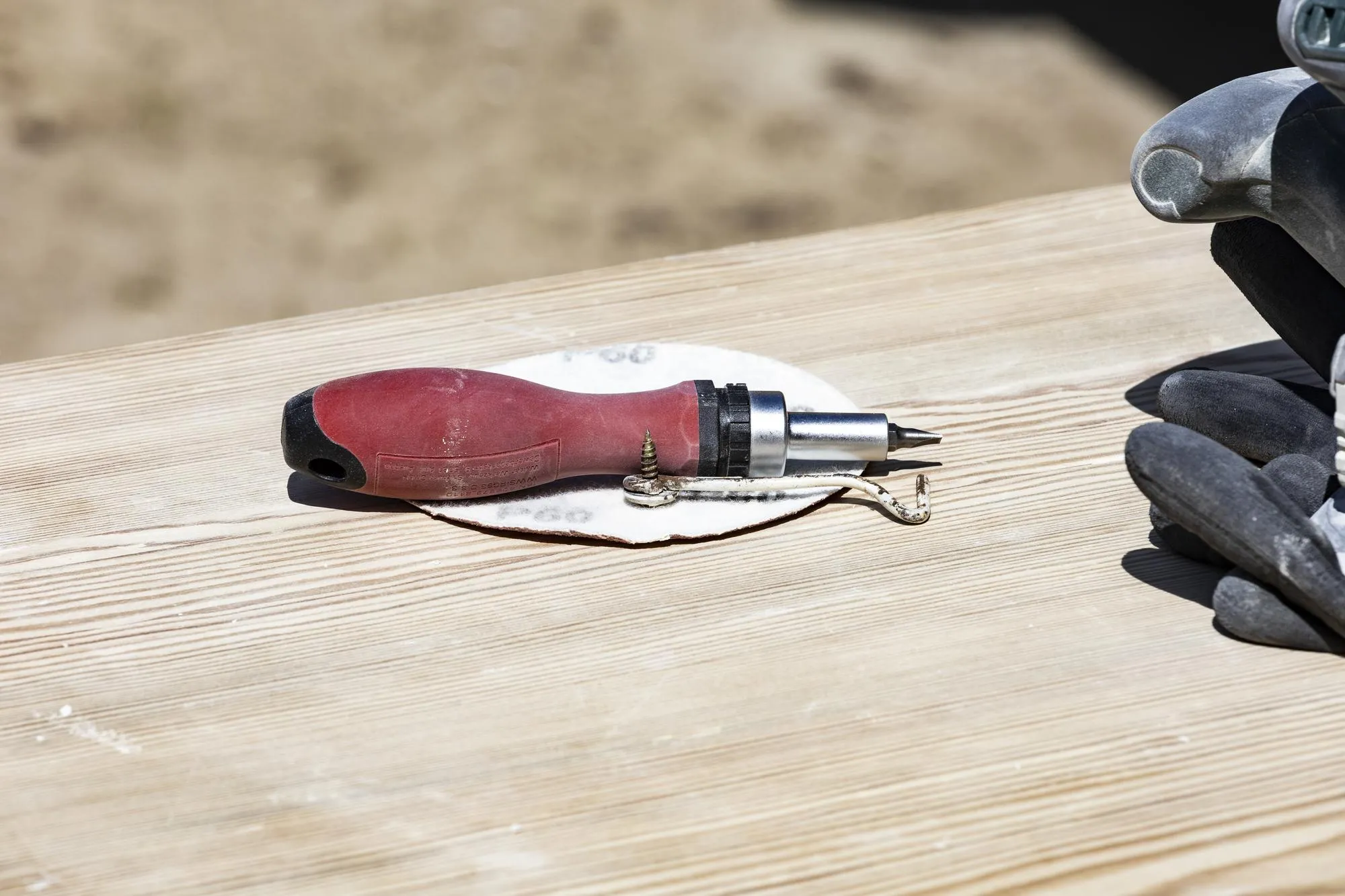 A red and black tool is on a wooden table.