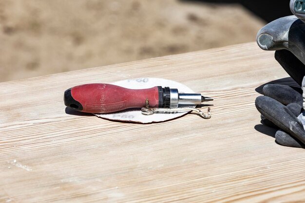 A red and black tool is on a wooden table.