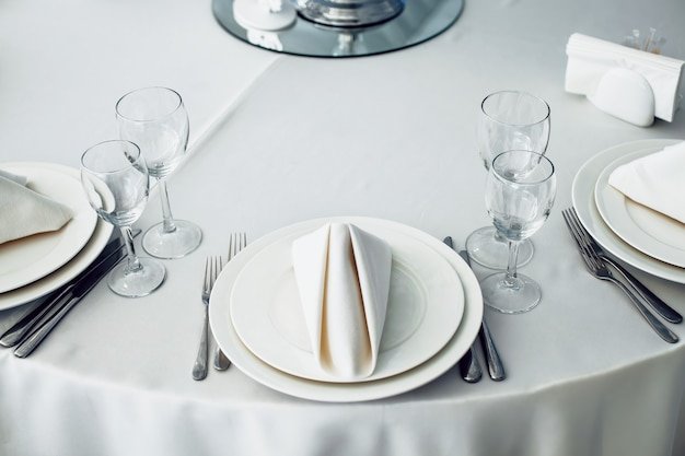 Restaurant tables set for celebration with plates cutlery napkin and glasses