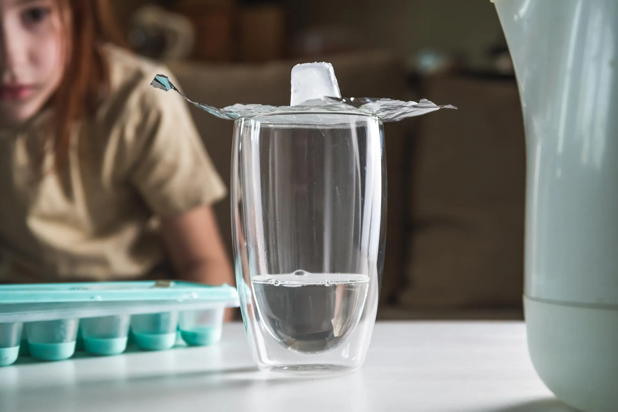 A schoolgirl conducts an experiment with hot water and ice