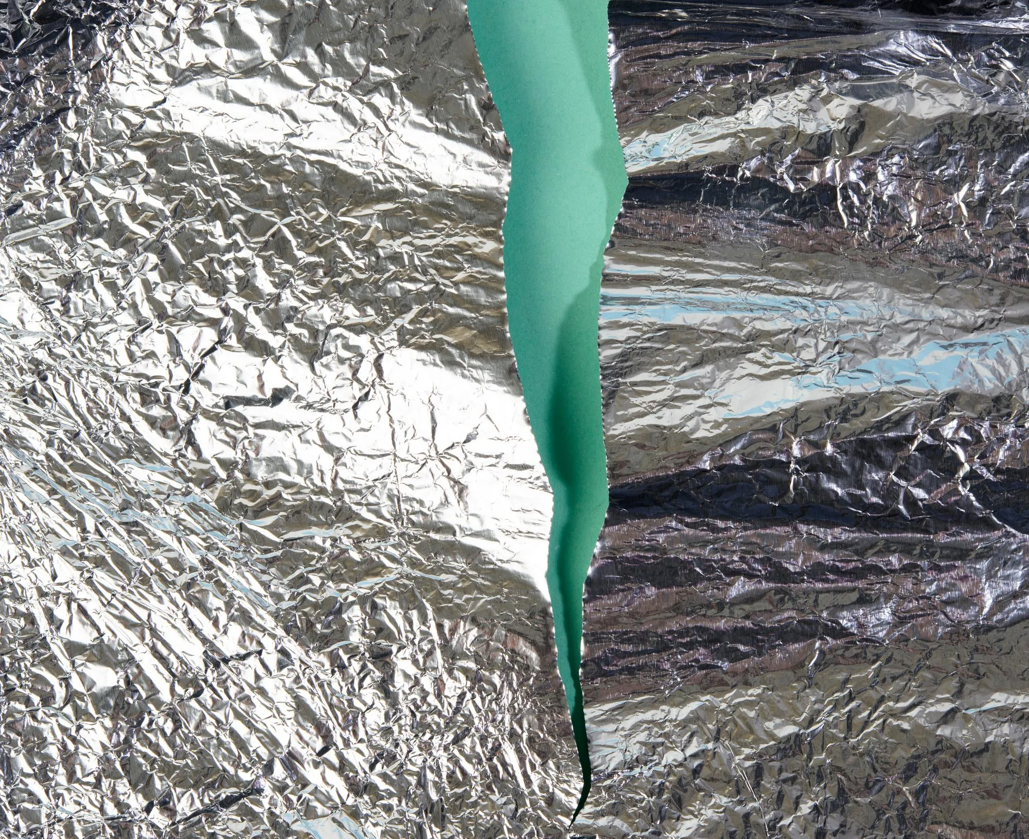 Torn pieces of foil on a green background close up
