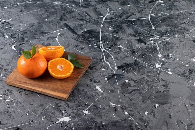 Whole fresh orange fruit with leaves placed on a wooden board