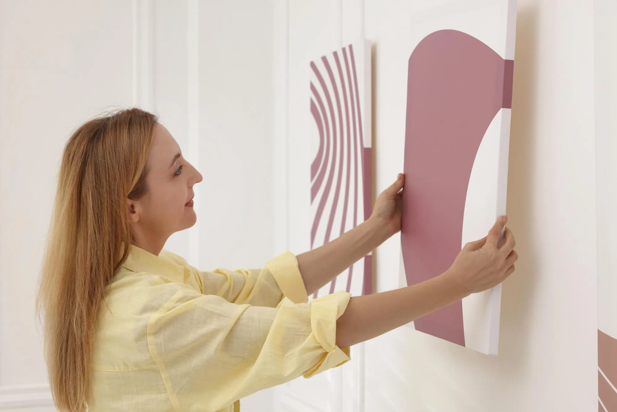 Woman hanging painting on wall in art gallery