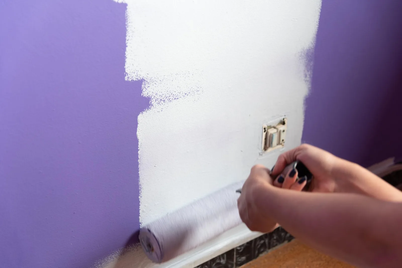 Young woman secures painting roller handle with hands to apply paint to wall with strength