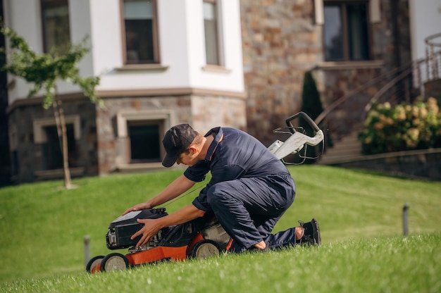 Fixing the lawn mover sitting Professional gardener is on the lawn